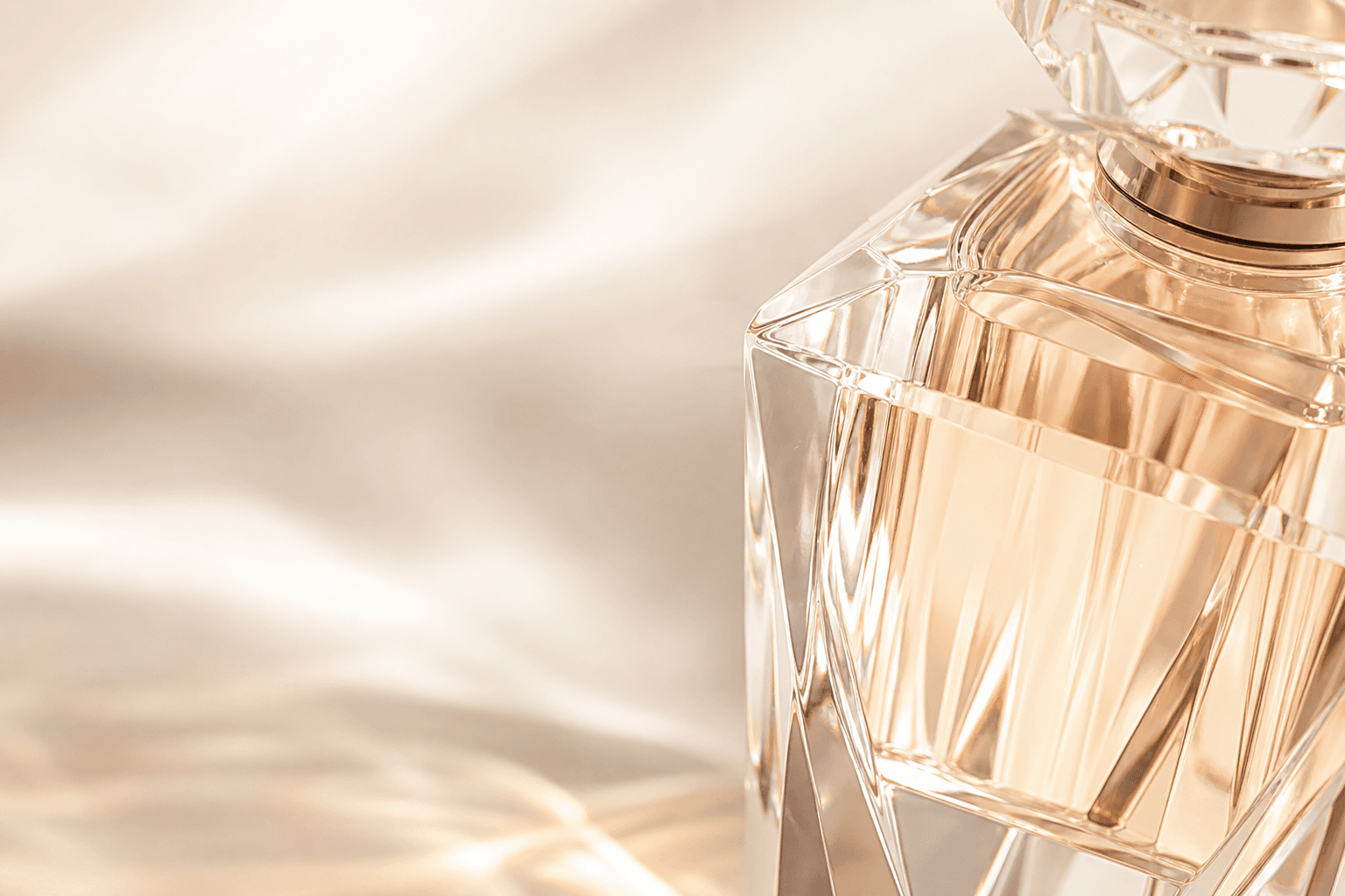 Crystal perfume bottle facets catching soft champagne light
